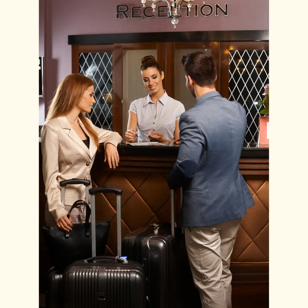 Hotel guests checking in at reception, interacting with front-desk staff in a hospitality setting.