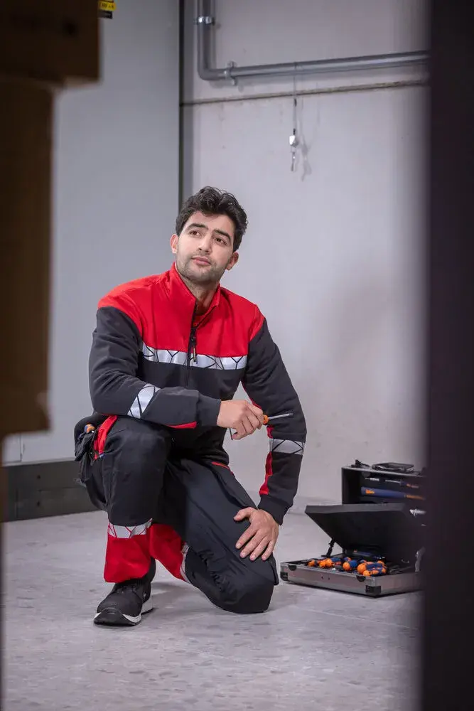 Mechanic wearing recycled and organic workwear sweatshirt while kneeling with tools