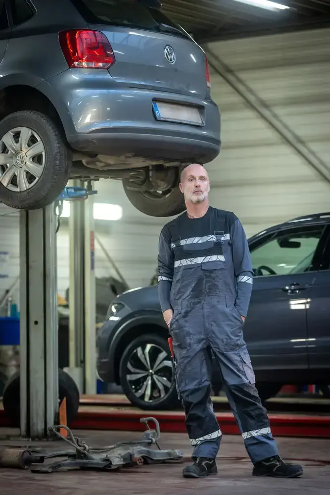 Mechanic wearing recycled bib and brace overalls while working in a garage