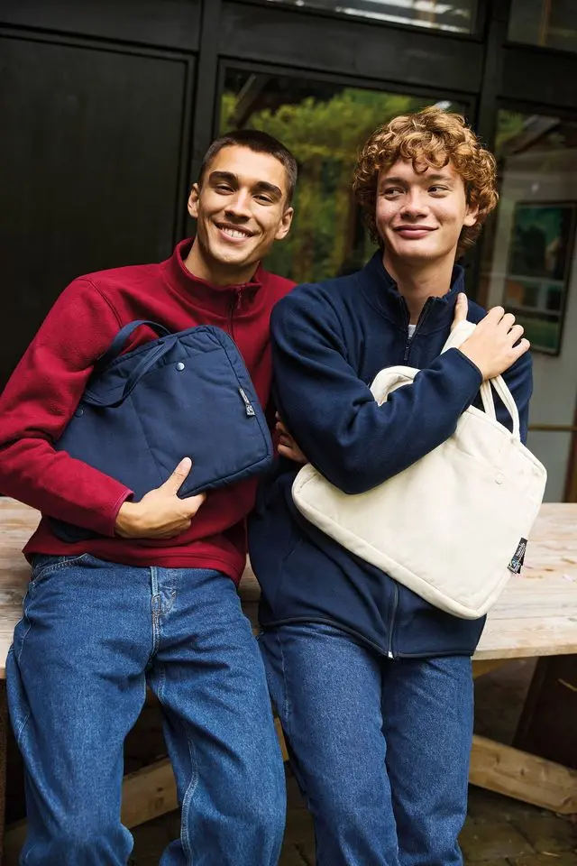 Image of two people wearing fairtrade  jackets and  holding fairtrade bags